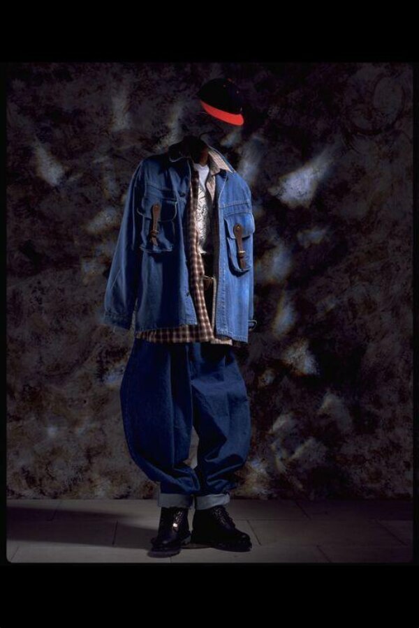 The American B-Boy outfit: blue and red baseball cap above a plaid shirt worn under a denim jacket, oversized jeans turned up over black boots