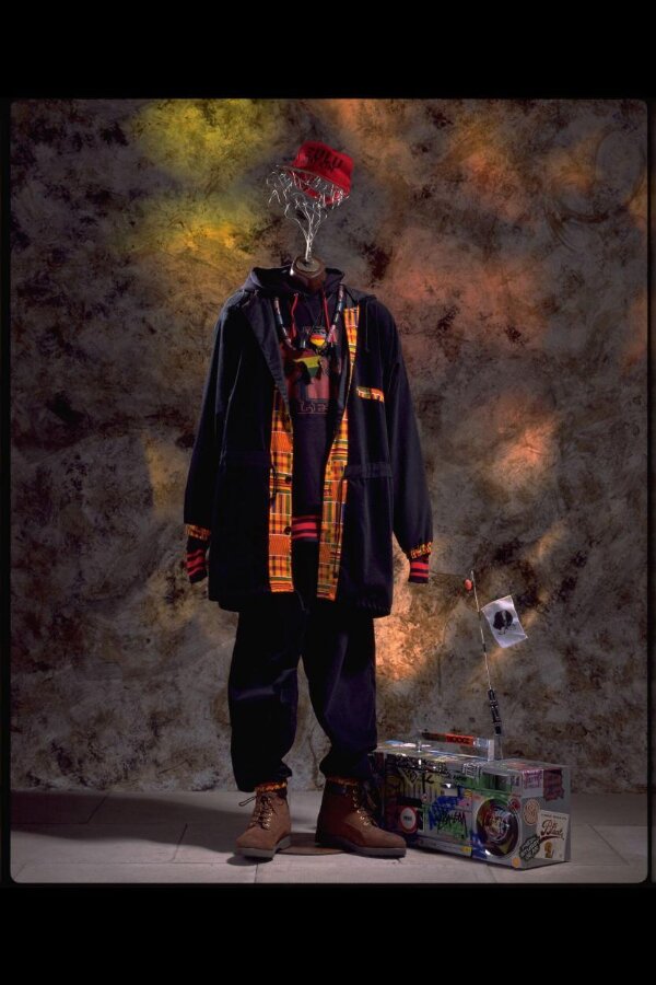 The Afrocentric B-Boy outfit on display: red and green cap, Malcolm X sweatshirt, Kente-trimmed corduroy suit, tan Timberland boots