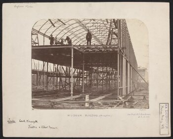 Exterior view of the South Kensington Museum (the 'Brompton Boilers') under construction, looking south with the houses of Cromwell Road and Thurloe Square visible in the background