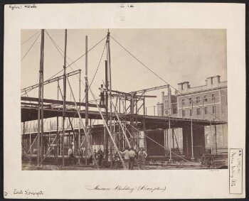 Exterior north east view of the South Kensington Museum (the 'Brompton Boilers') under construction, Holy Trinity Church, Brompton tower and Oratory House of the London Oratory in the background