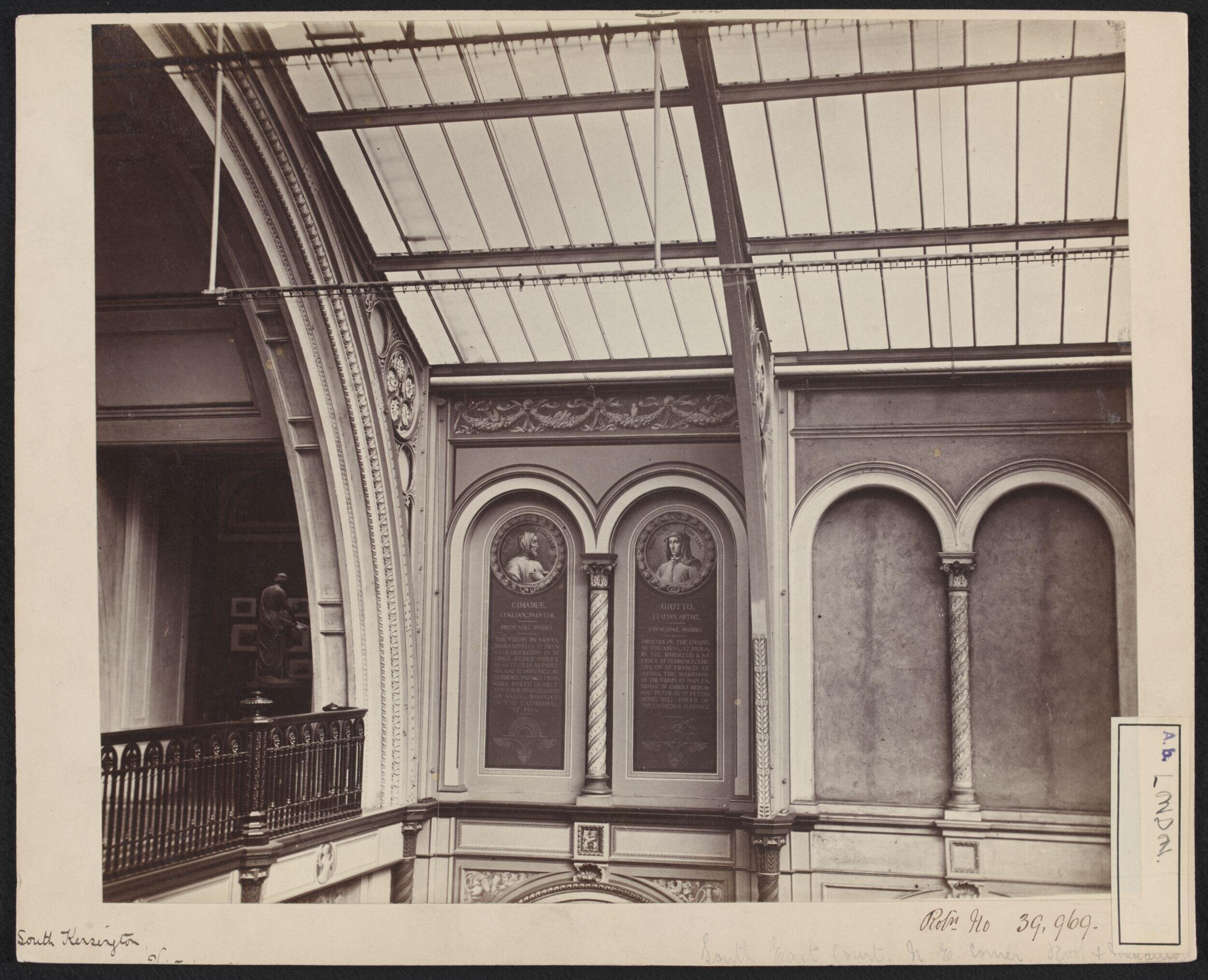 Interior view of the South Kensington Museum, north east corner of the South Court with partial view into Gallery 99, showing trial decoration with portraits of artists in roundels