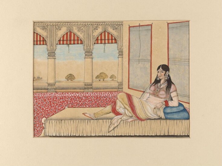 An Indian lady reclining on a couch in the open verandah of a palace. top image