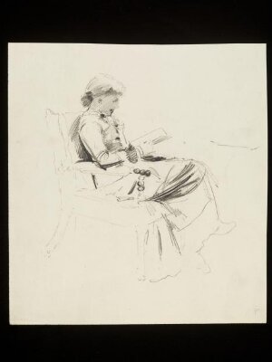 A woman seated in a chair reading a book