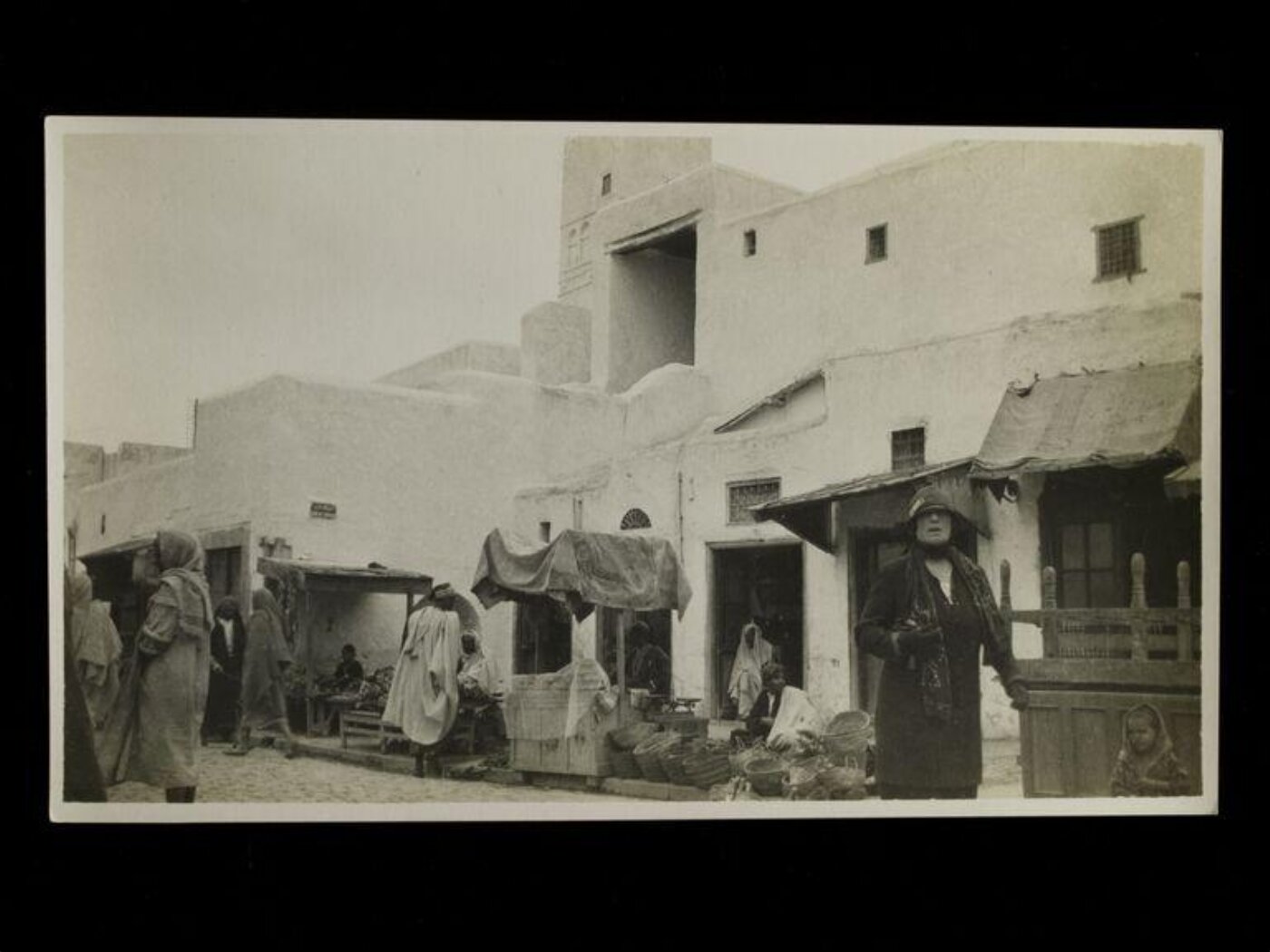 Unknown, A street scene in Kairouan, Algeria, with a European woman in the foreground.