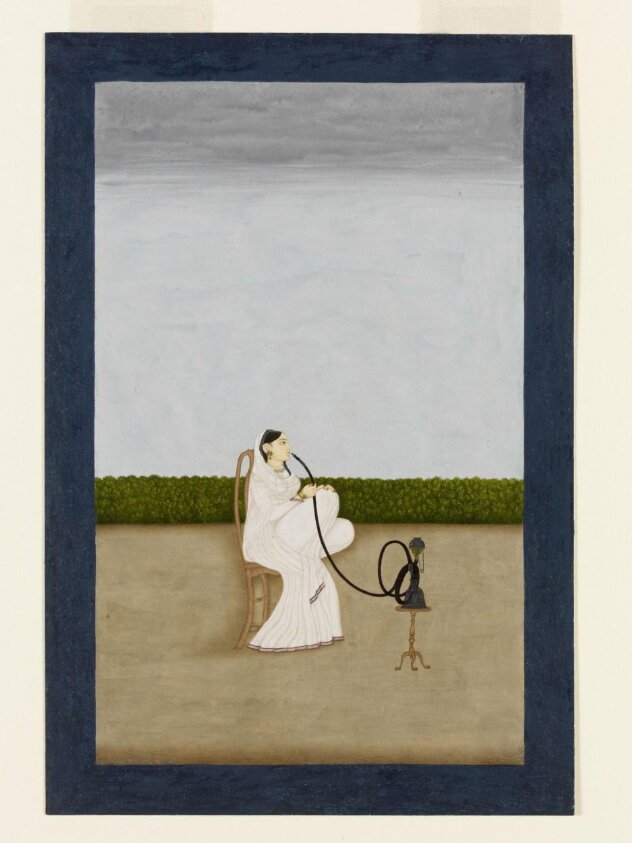 A seated woman smoking a huqqa