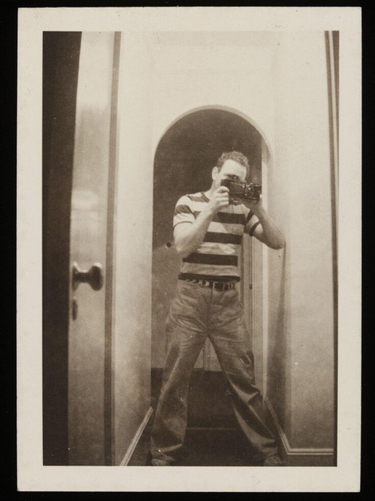 Man in a striped t-shirt using a camera top image