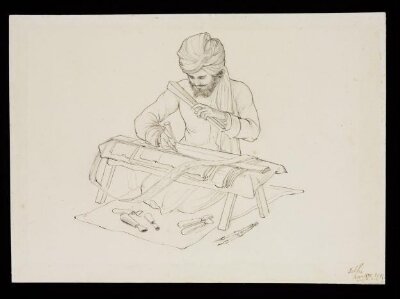 A man stamping a gold and silver lace design on a small trestle