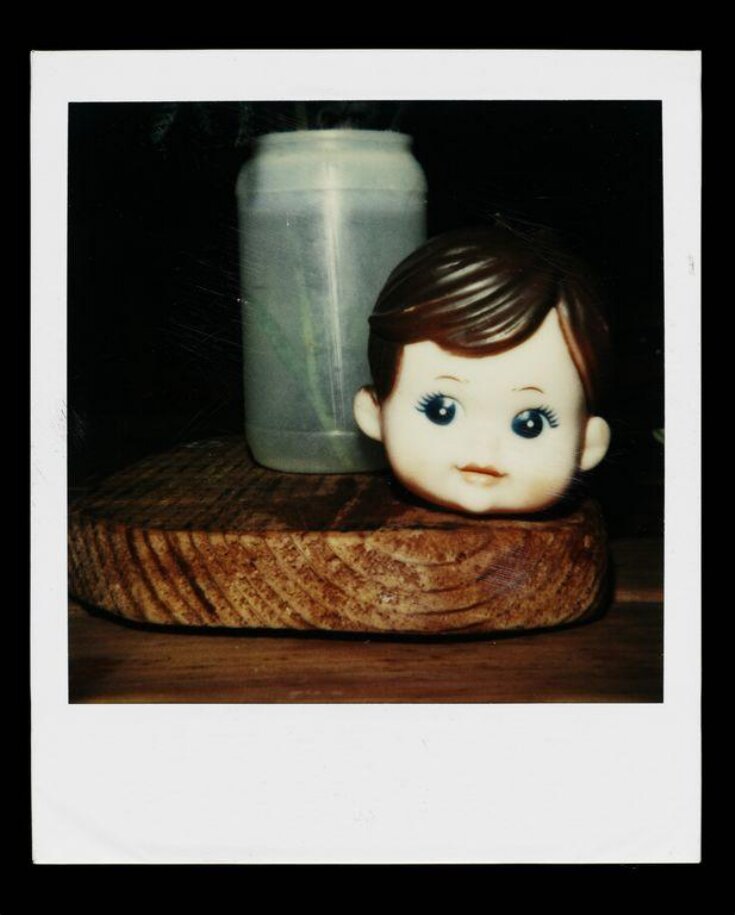  Untitled, (Polaroid of a dolls head next to a plastic container) top image