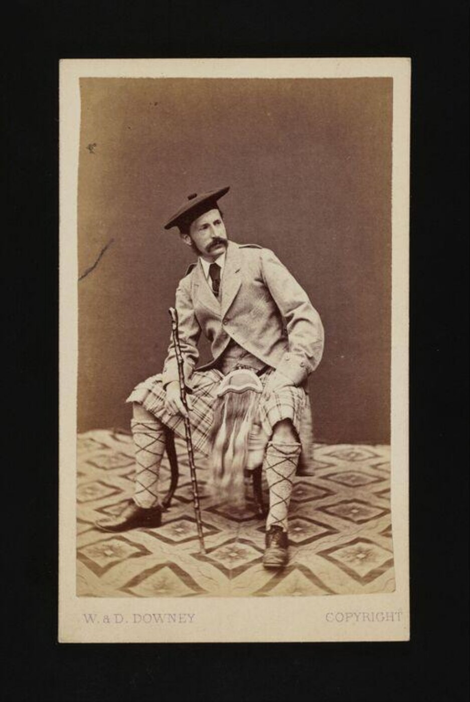 W. & D. Downey, Man in highland dress, seated, holding a walking stick
