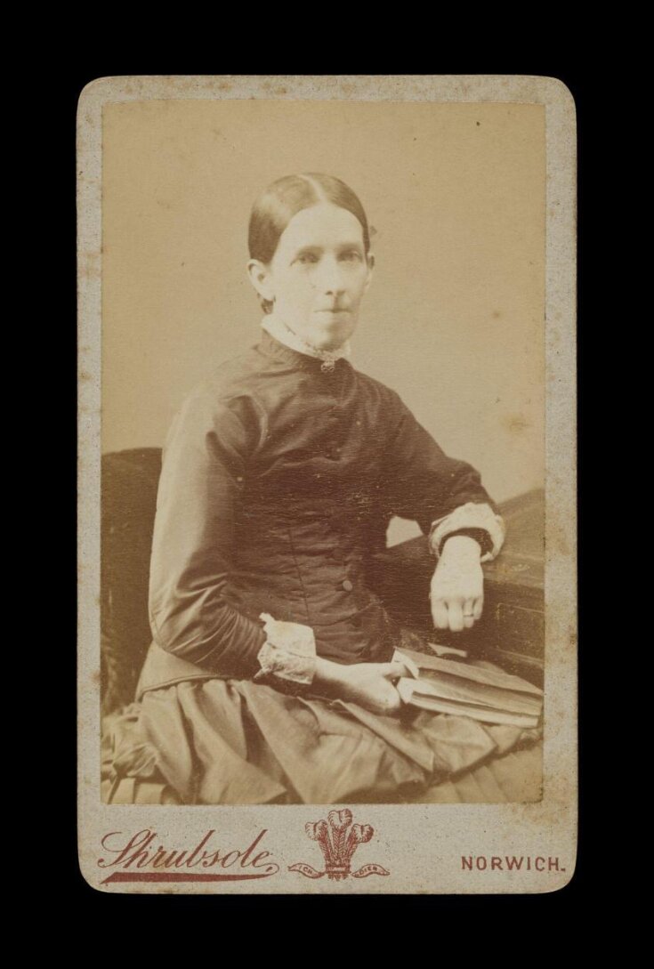 Portrait of a woman seated holding a book top image