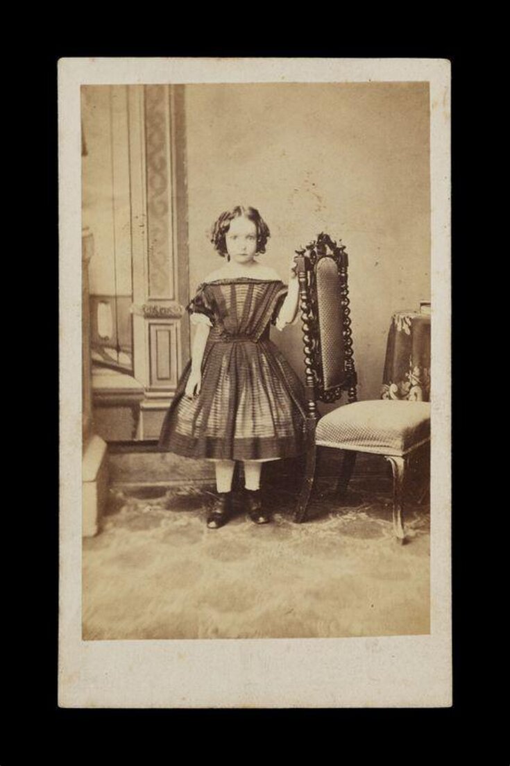 young girl standing next to a chair top image