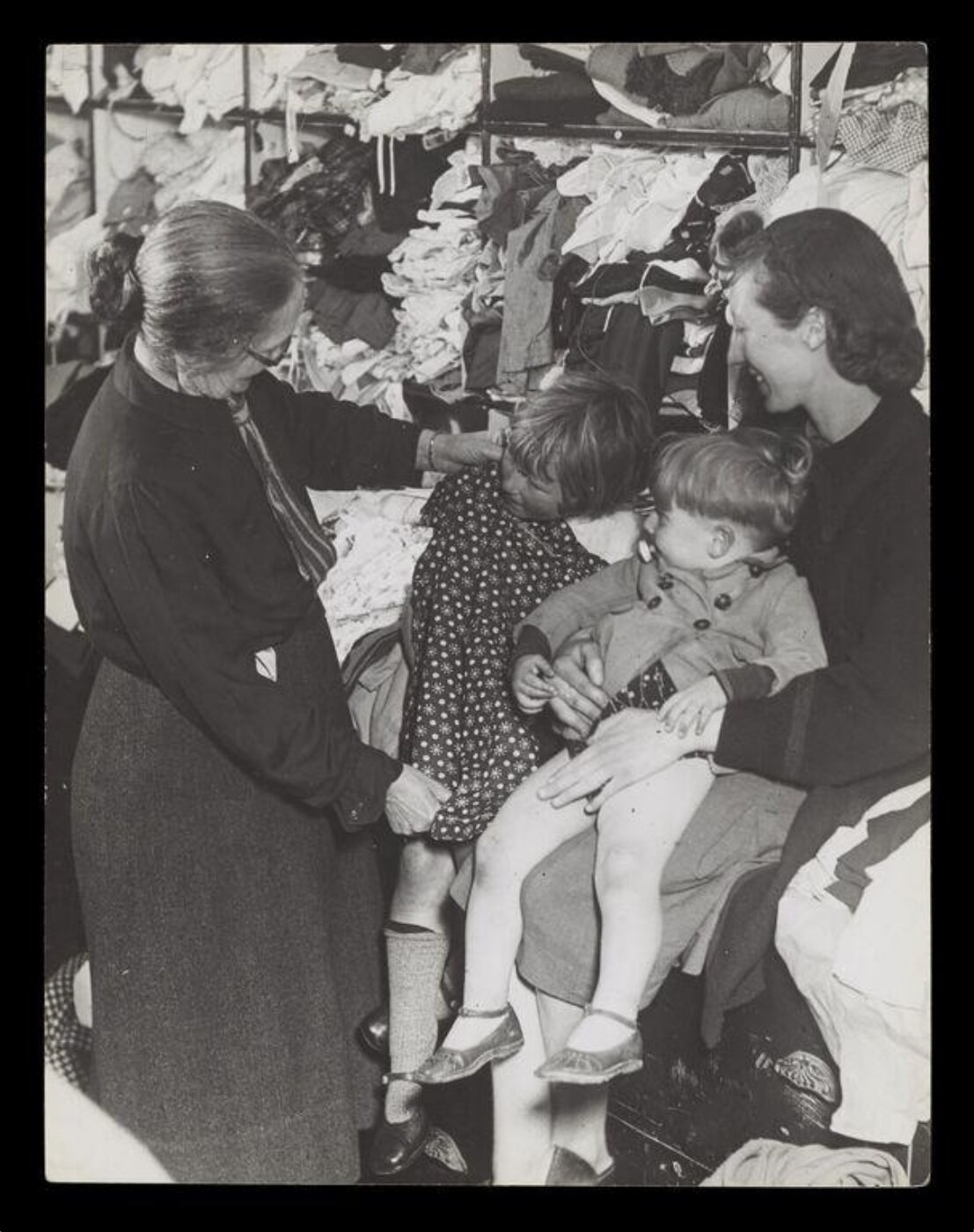 Hinde, John Wilfrid, A W.V.S. Worker Selecting a Frock for a Little Girl